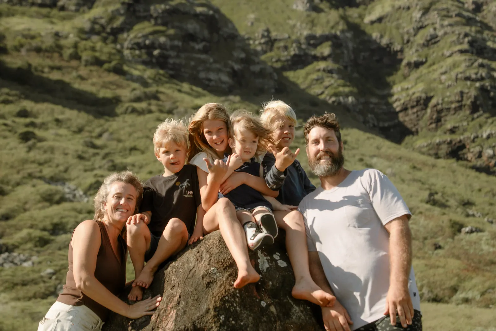 The whole ohana sitting together on a boulder