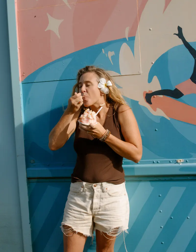 Taking the first bite of a shave ice in front of the mural